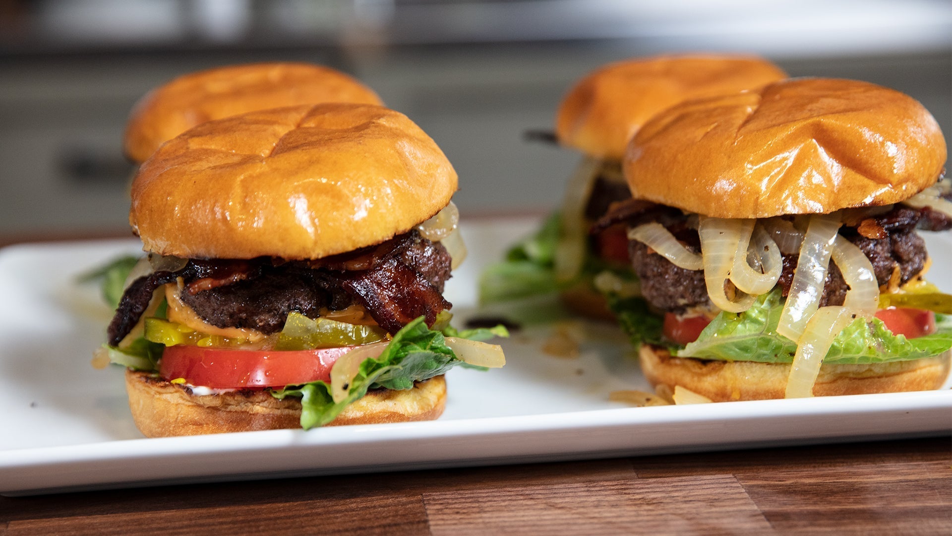 Four burgers on a white plate ready to serve