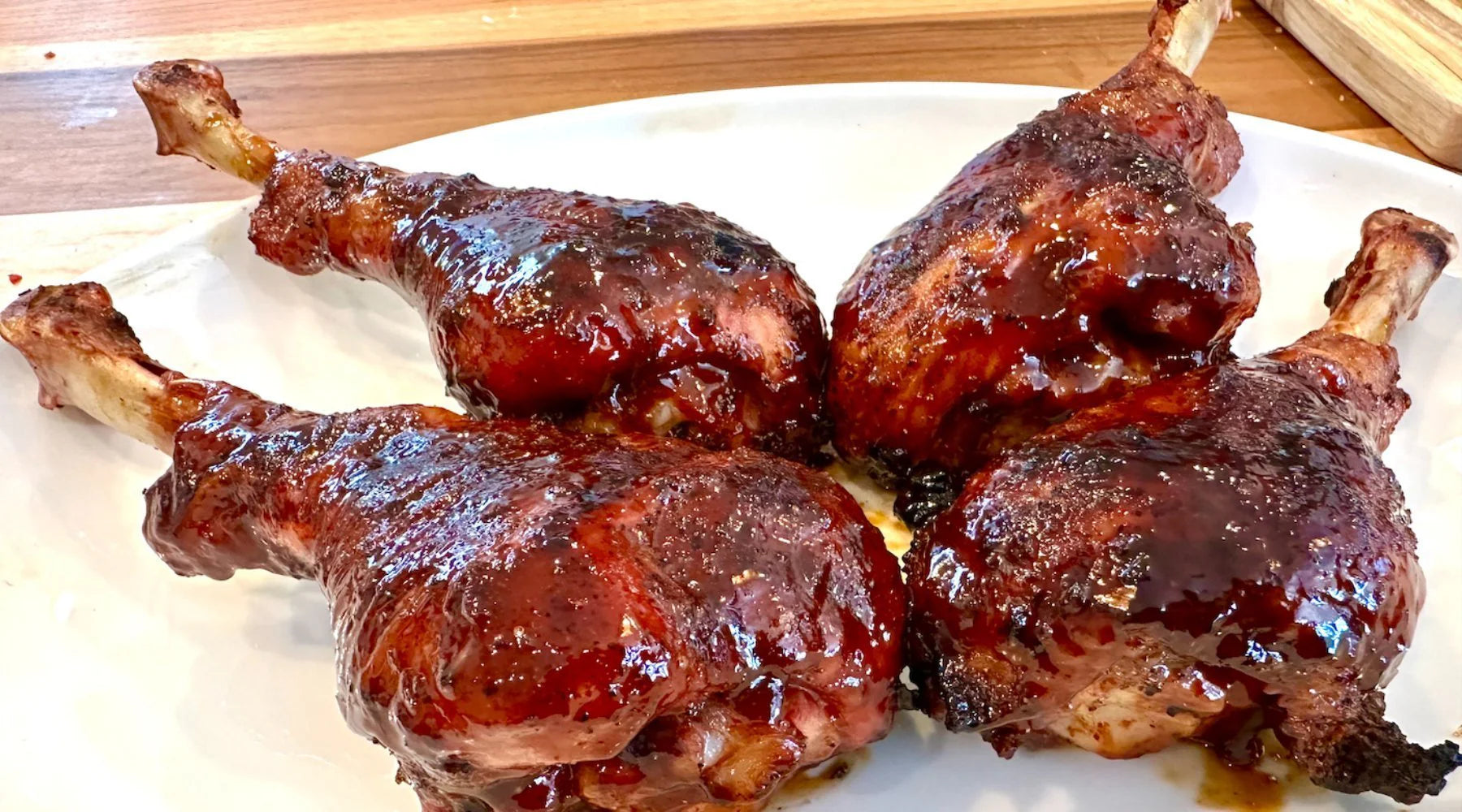 Braised chicken legs on a white plate with a wooden surface in the background