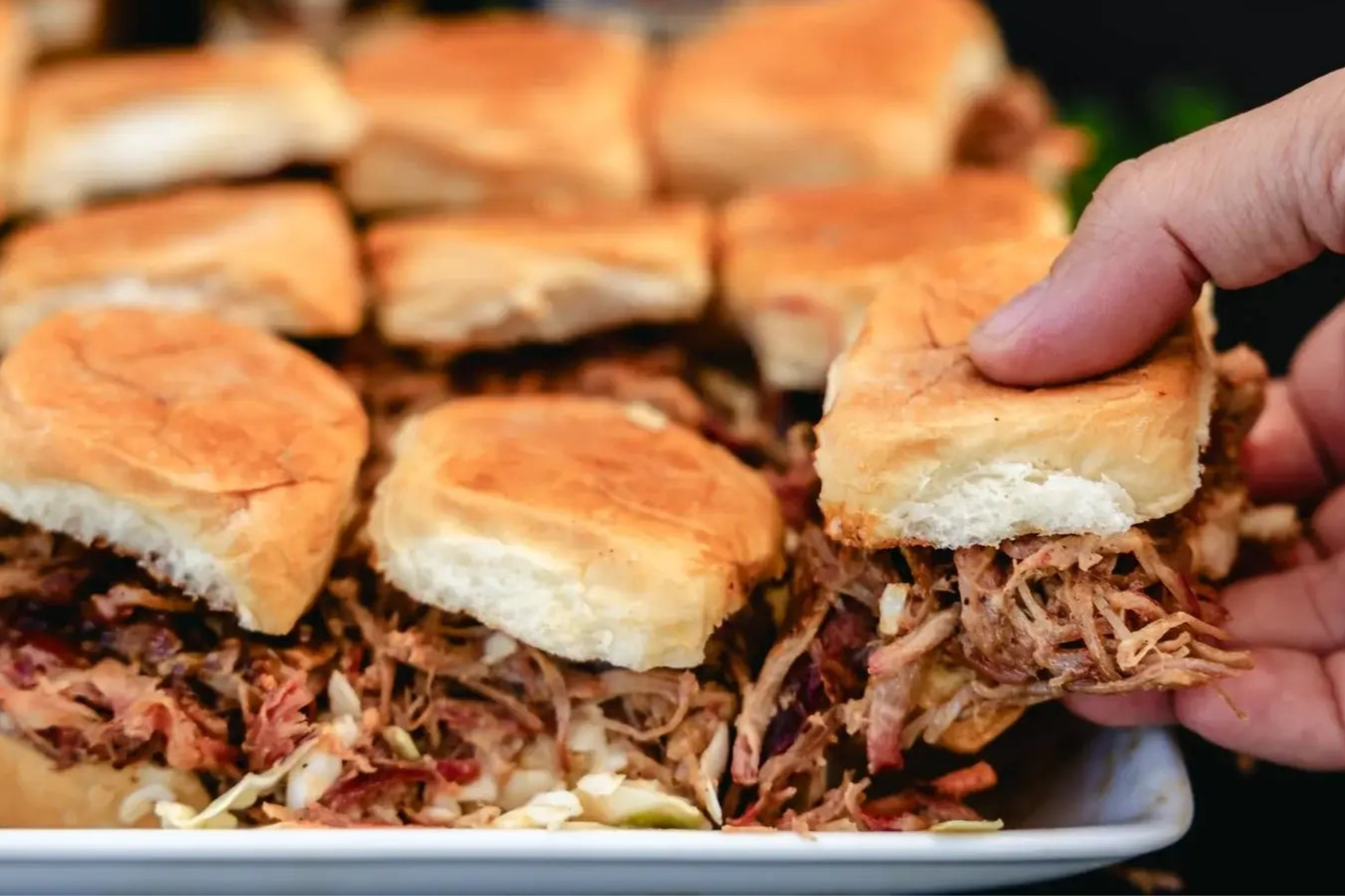Picking up a pulled pork slider with slaw