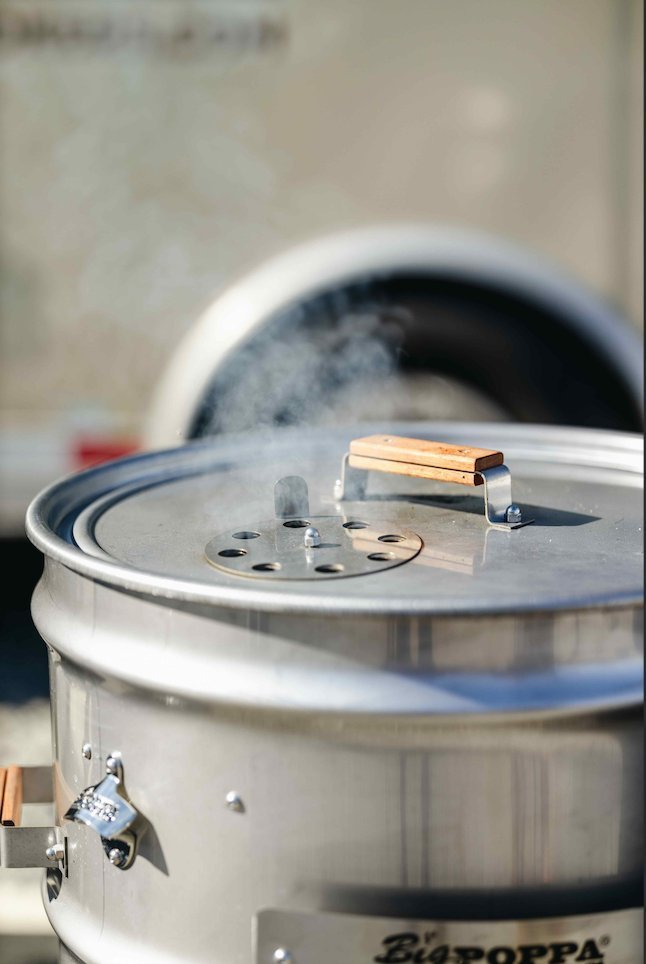 Close-up of the stainless steel pre-drilled drum with textured surface and visible drainage holes for even smoking.