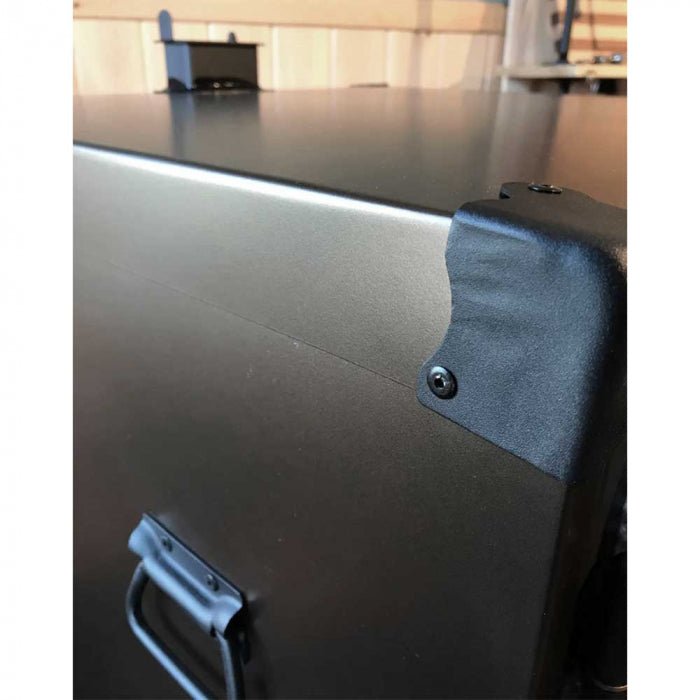 Close-up of the Qube'd Box's textured metal surface with engraved branding and precise corner welds highlighting durability