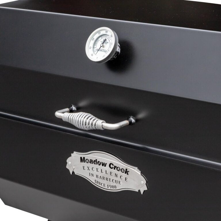 Close-up of the black temperature gauge and shiny stainless steel lid handle on the Meadow Creek PR36 Pig Roaster from a