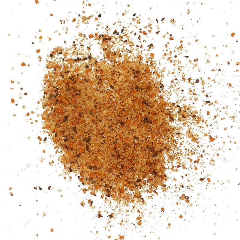 Close-up of hand-rubbed Smokin' Guns BBQ Hot Rub seasoning on meat, highlighting its vibrant spice blend and textured